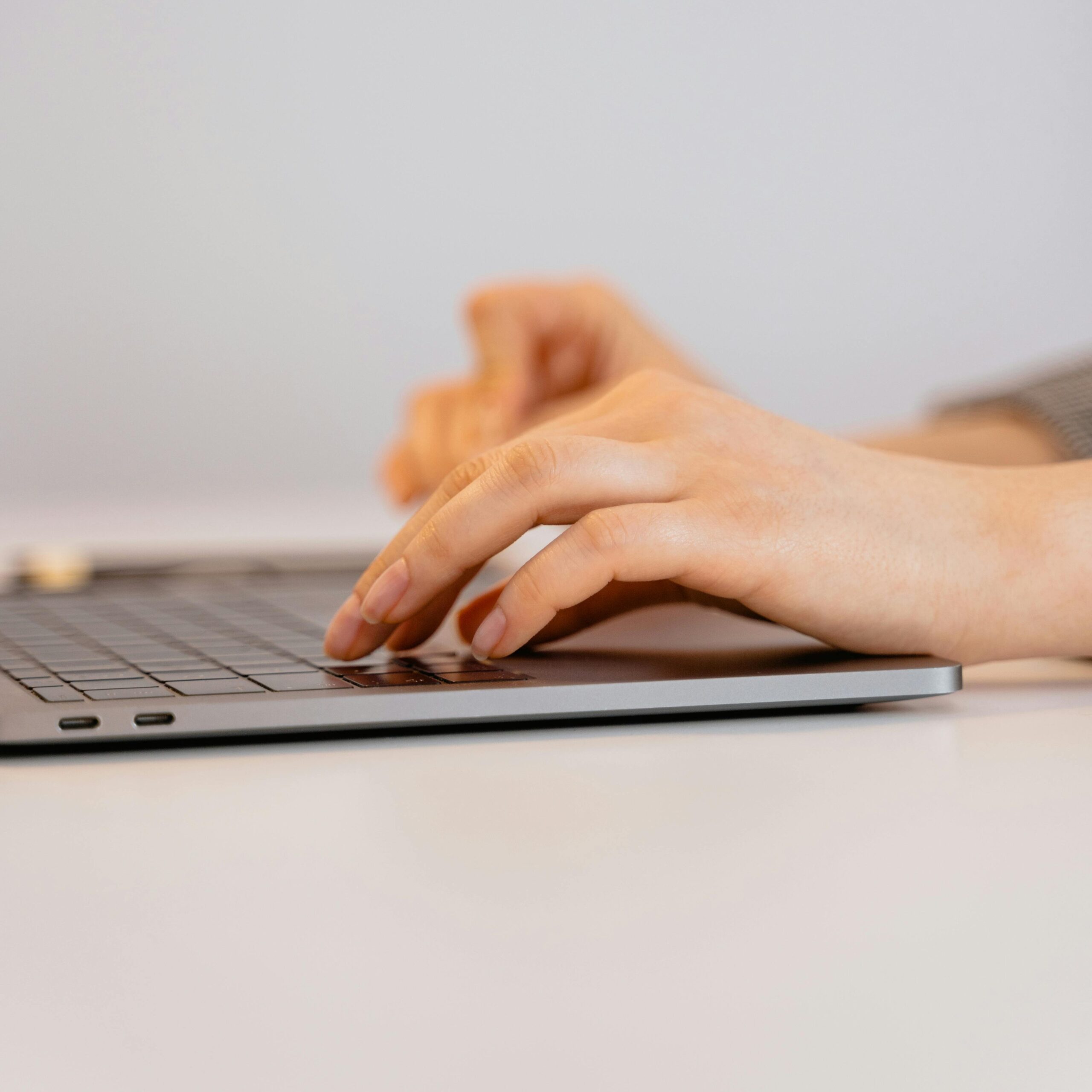 Hands typing on a laptop keyboard, focusing on digital connectivity and remote work.