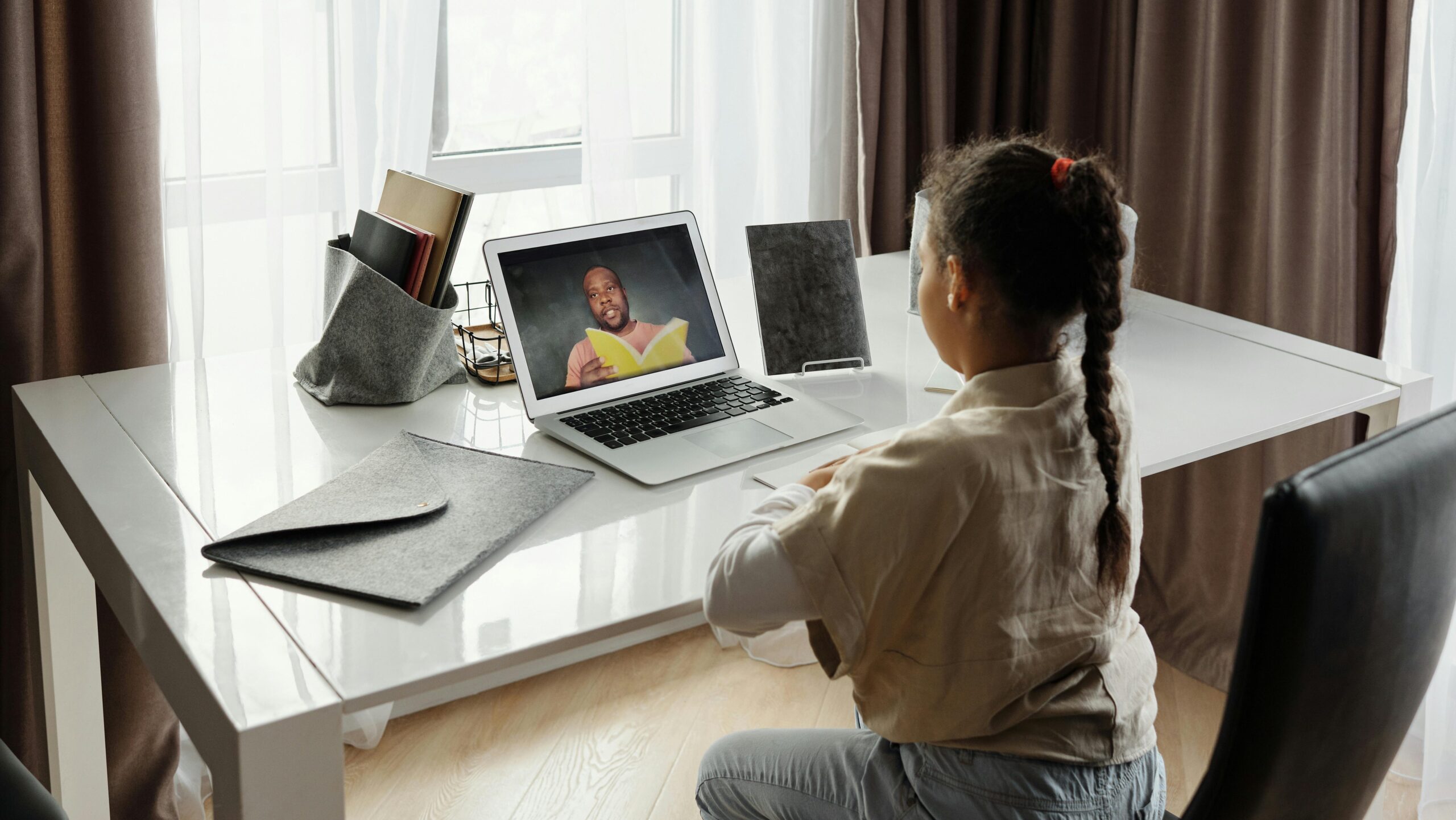 Young girl engaged in a virtual learning session at home with a teacher on video call.